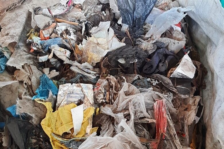 Verschiedene Abfälle aus Plastik und Papier, unsortiert in einem Container, zur Veranschaulichung von Mülltrennung und Recycling.