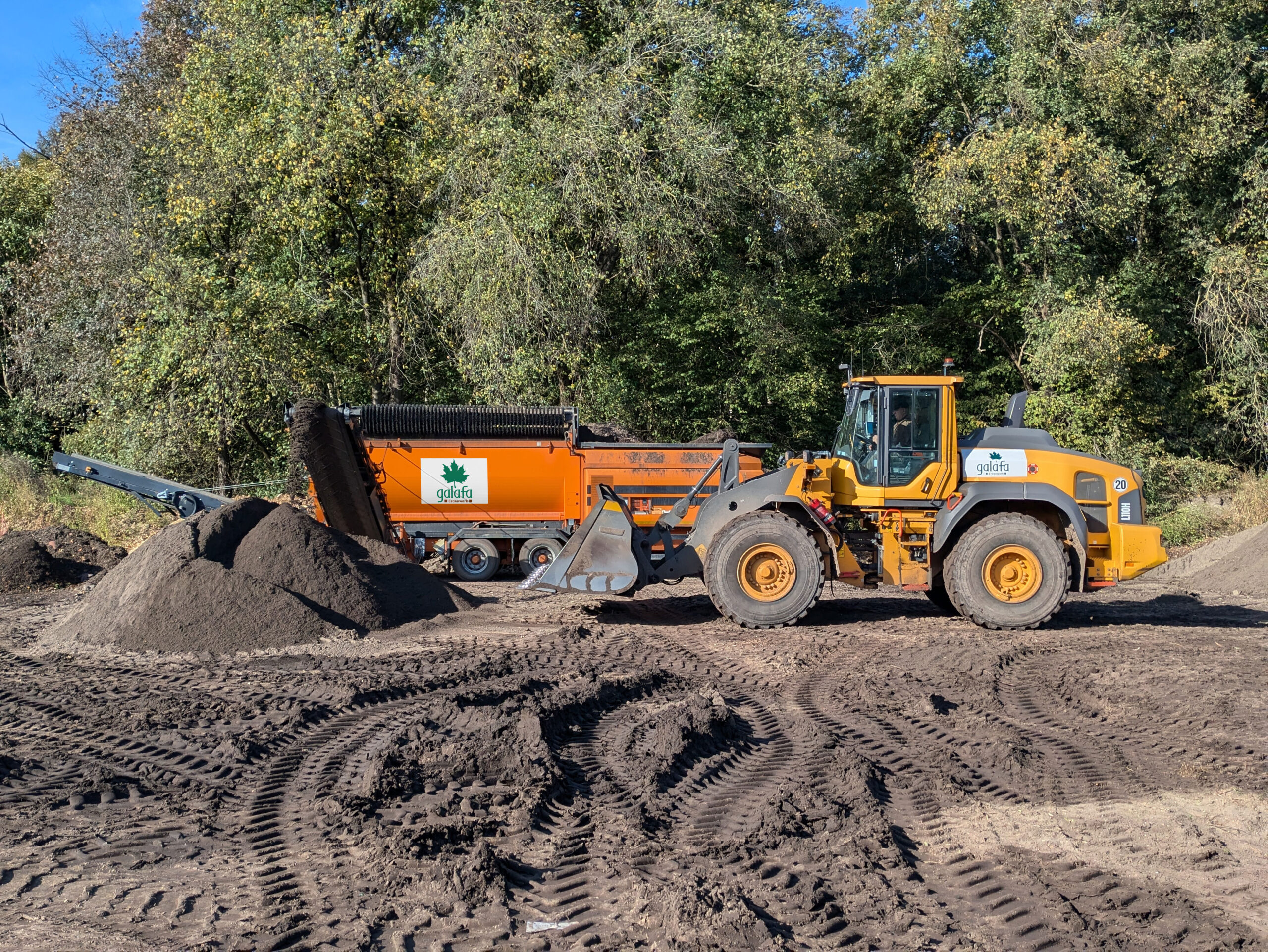 Radlader von Galafa bei der Arbeit mit einer großen Sand- und Erdmulde auf einer Baustelle.