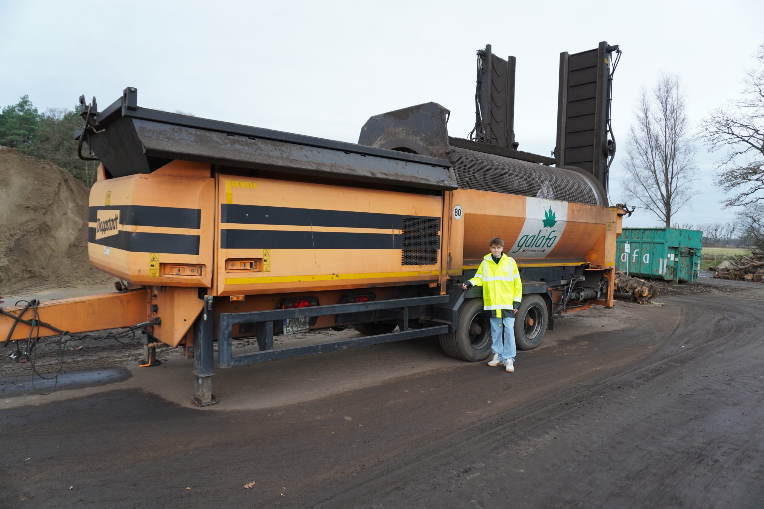 DSC00074 Lkw der Marke Galafit mit einer großen Maschine zur Bodenbearbeitung, daneben steht eine Person in einer leuchtend gelben Sicherheitsjacke.